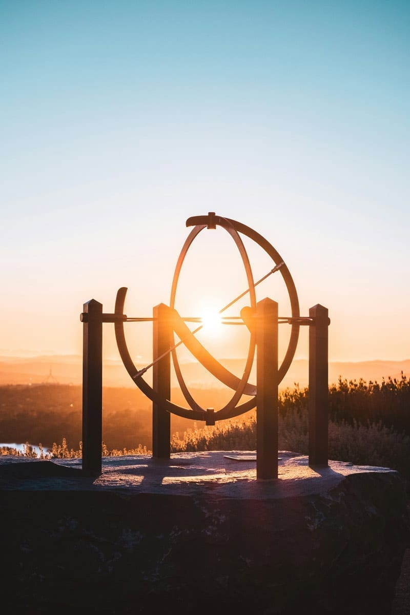 Sunrise behind a sundial sculpture overlooking Canberra